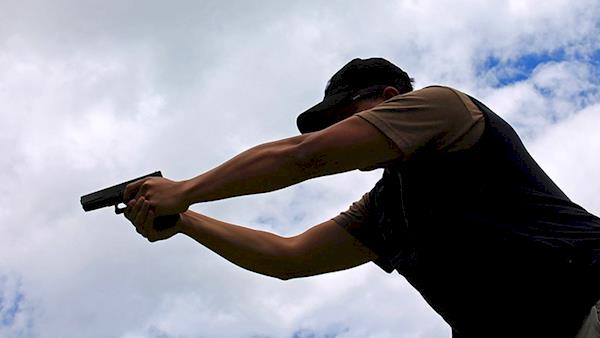 Silhouette of a Man Shooting a Pistol Outside